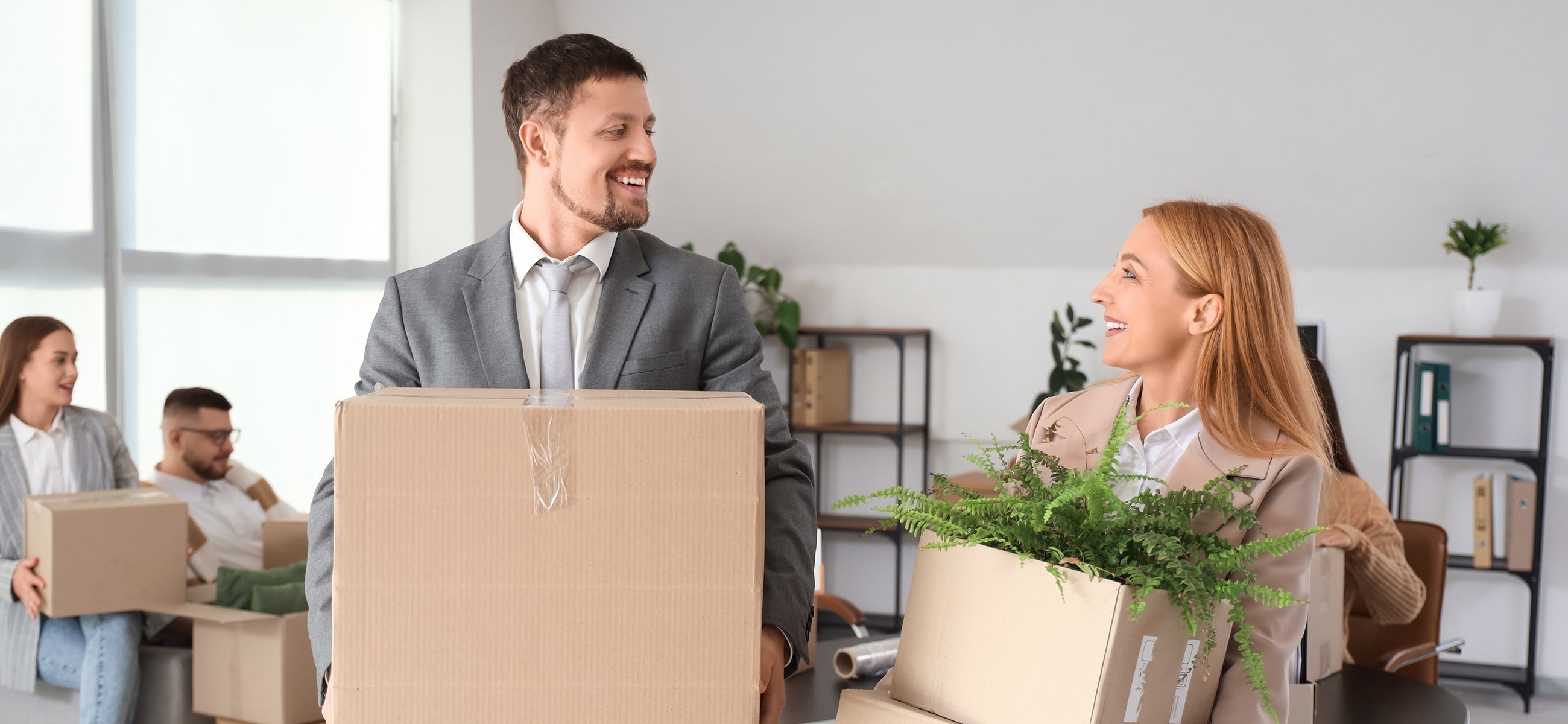 Ein Mann und eine Frau tragen Umzugskartons aus einem Büro
