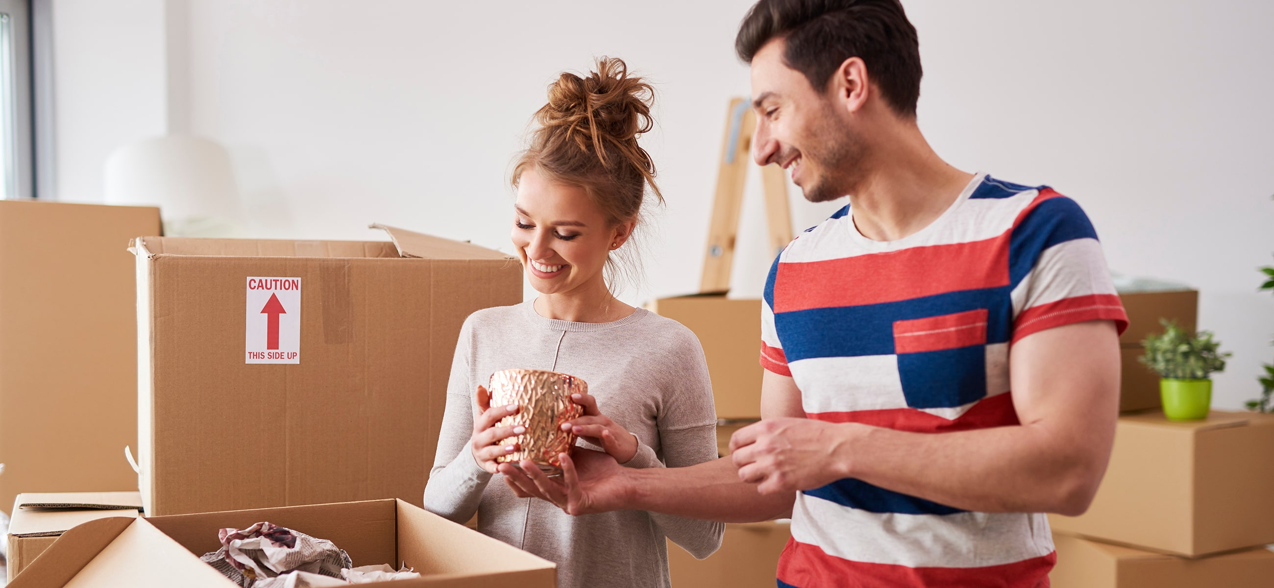 Mann und Frau packen einen Gegenstand in einen Umzugskarton
