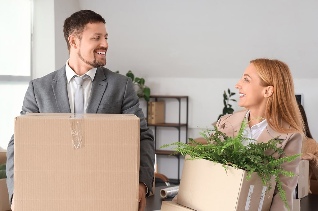Zwei Menschen tragen Kartons im Büro
