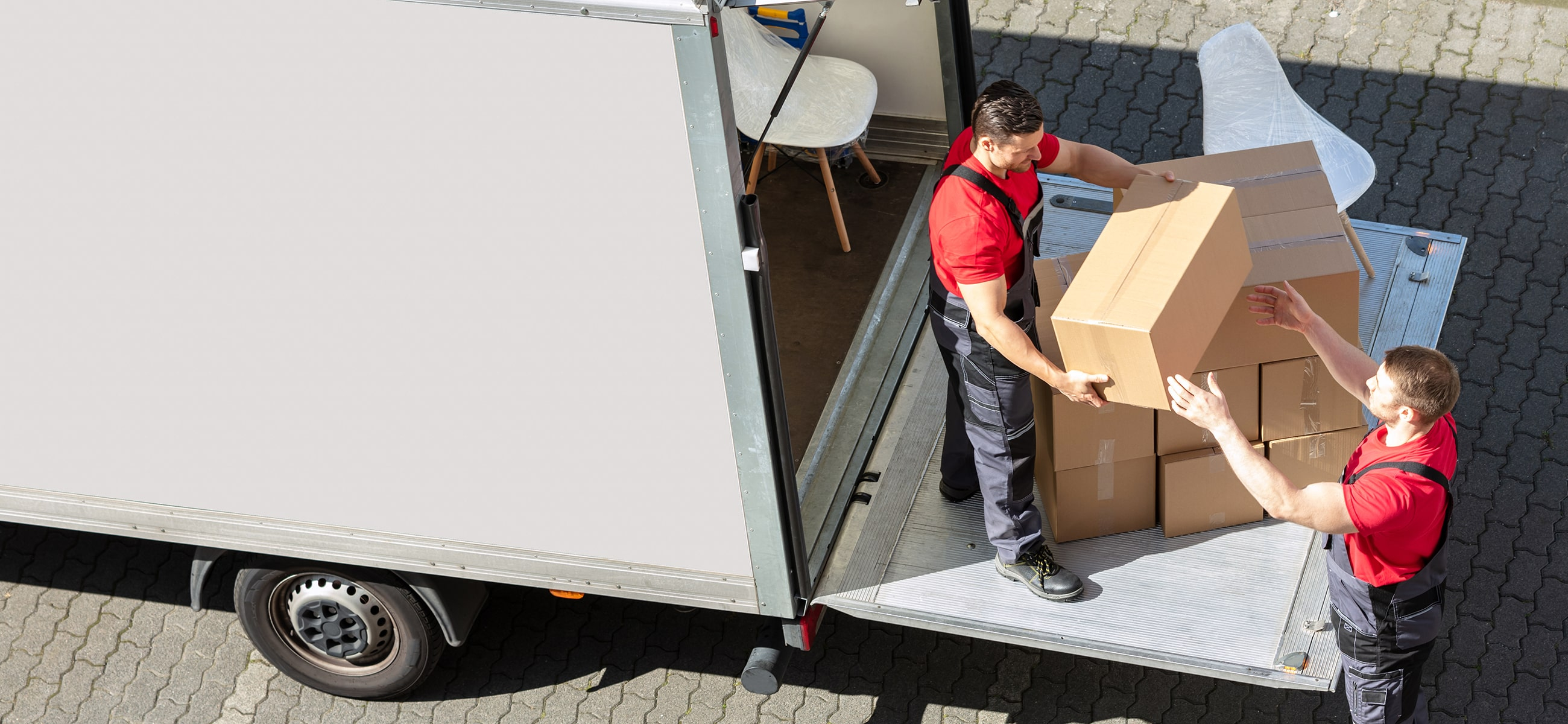 zwei Umzugshelfer laden Umzugskartons aus einem LKW aus