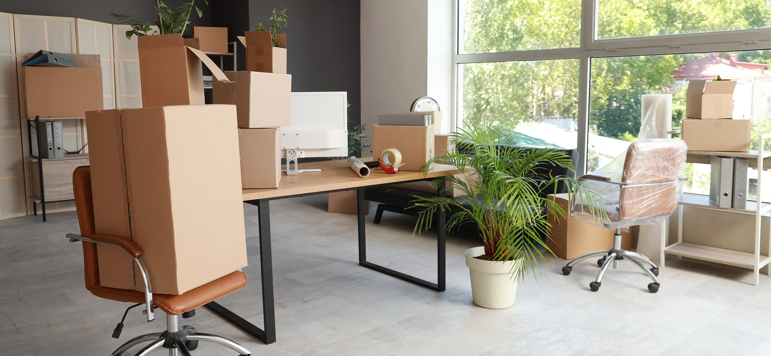 Umzugskartons und verpackte Möbel stehen in einem Büro bereit für den Umzug