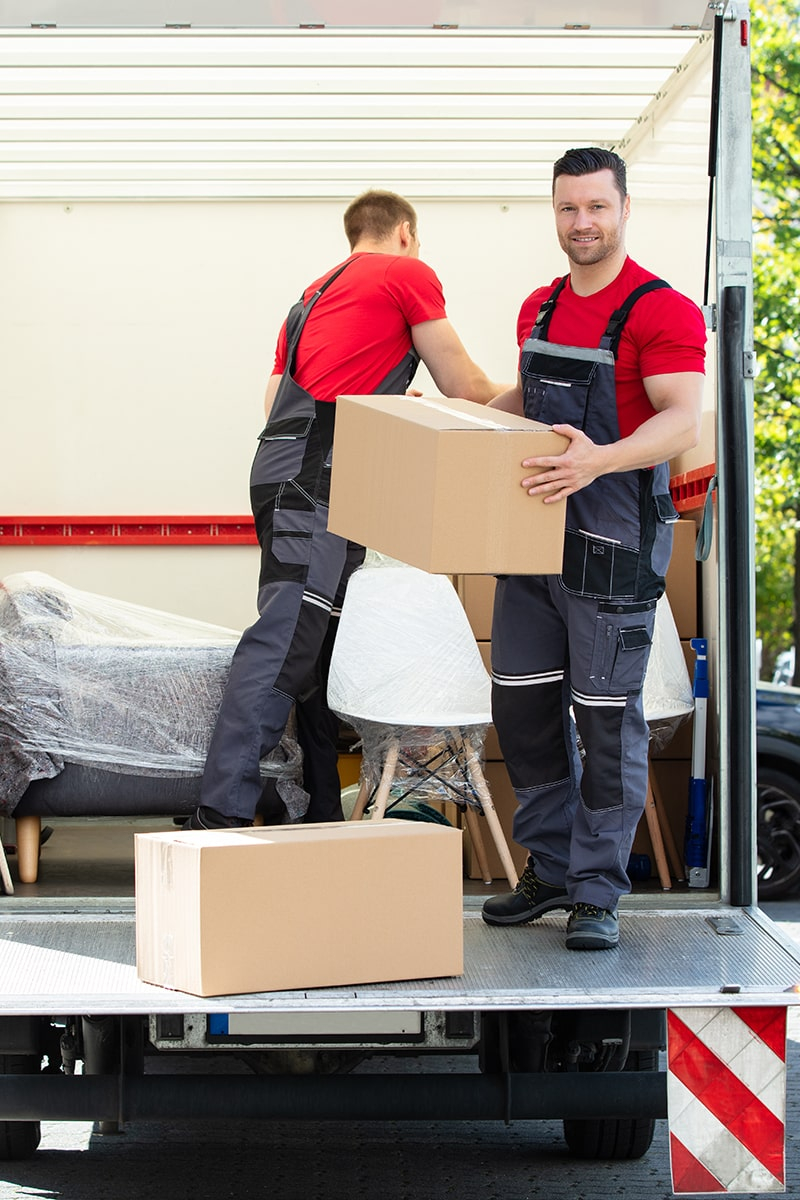 Zwei Umzughelfer laden Umzugsgut aus einem LKW aus